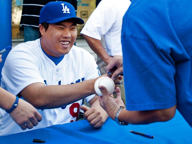 Hyun-Jin Ryu, the Dodgers' newest pitcher, signs a ball for life-long fan Joe Hiraga of Monterey Park on Tuesday outside the Radio Korea building.