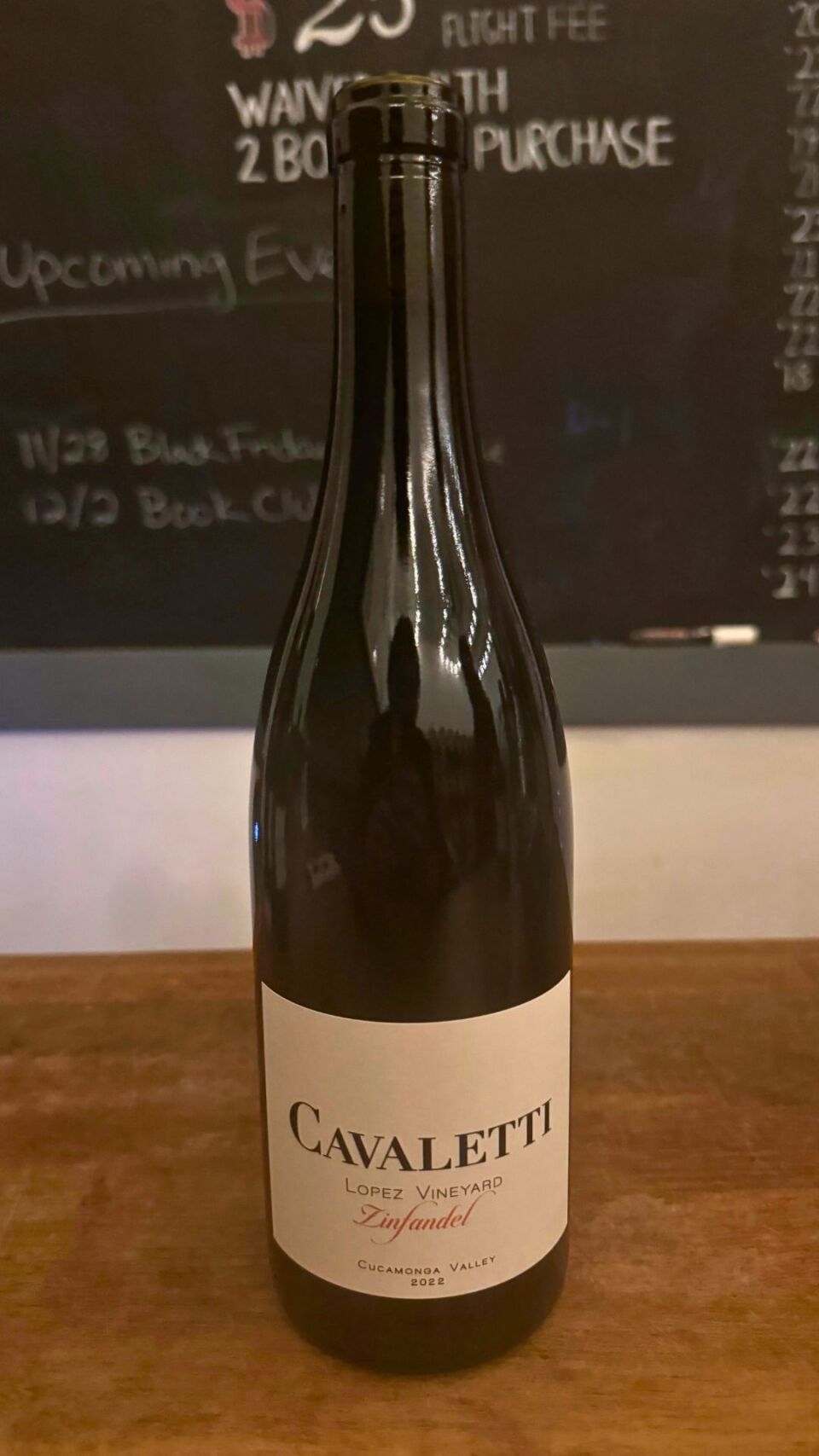 A bottle of wine on a wooden counter top that has the word "CAVALETTI" on the label. 