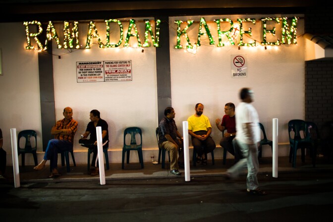 At the beginning of the final week of fasting, members of the Islamic Center of Southern California in Koreatown visit under a sign that translates to, "Have a generous Ramadan."