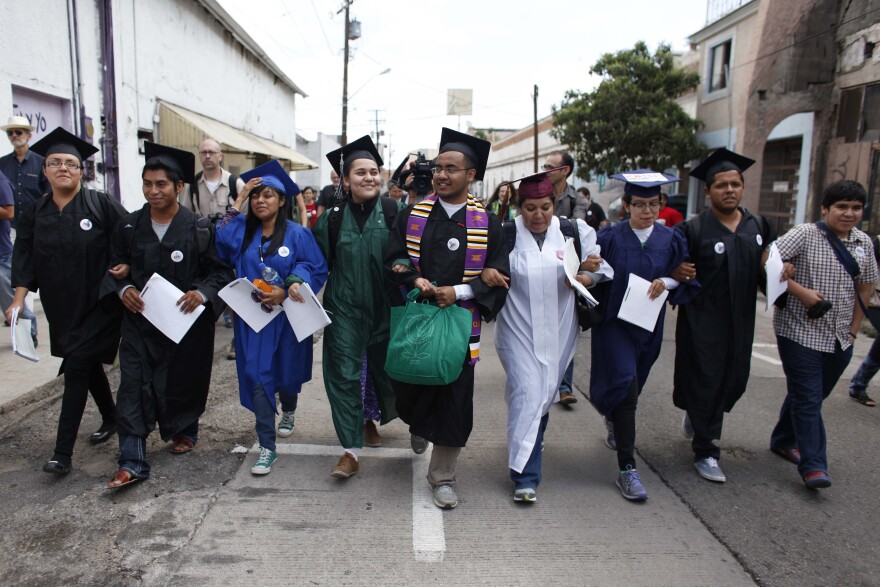 Eight "Dreamers" wearing their school graduation caps and gowns to show their desire to finish school in the U.S., march with linked arms to the U.S. port of entry where they planned to request humanitarian parole, in Nogales, Mexico, Monday, July 22, 2013. U.S. border officials later detained the group who asked to be allowed to re-enter the United States from Mexico on humanitarian grounds in a protest against the country’s immigration policies.