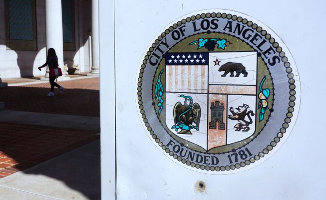 A woman walks through a plaza in front of City Hall in Los Angeles, California on August 22, 2017. 
The city of Los Angeles has sued the US Justice Department over threats to cut millions of dollars in federal funding for "sanctuary cities." The lawsuit joins similar legal challenges launched earlier this month by the city of San Francisco and the state of California against the department.   / AFP PHOTO / FREDERIC J. BROWN        (Photo credit should read FREDERIC J. BROWN/AFP/Getty Images)
