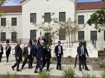 L.A. Mayor Karen Bass speaks with another person while walking outside a building at the West Los Angeles Veterans Affairs campus.