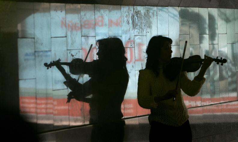 A street musician is reflected in a marble wall as she plays violin in a pedestrian subway in the center of Kiev 11 October, 2007. AFP PHOTO/ Sergei SUPINSKY (Photo credit should read SERGEI SUPINSKY/AFP/Getty Images)