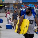 People walk near the Santa Monica Pier as crowds gather on Memorial Day as shutdowns are relaxed more than a year after Covid-19 pandemic shutdowns began, in Santa Monica, California on May 31, 2021. (Photo by DAVID MCNEW / AFP) (Photo by DAVID MCNEW/AFP via Getty Images)