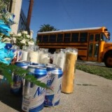A school bus passes a memorial of candles, flowers, and other sundries to a slain suspected gang member who was killed there on January 31, 2009.