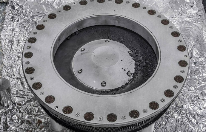 Small rocks and dust from an asteroid, outside a round sample collection device in a NASA lab.