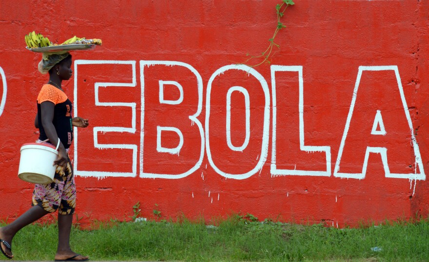 A seller of bananas walks past a slogan painted on a wall reading 'Ebola' in Monrovia on August 31, 2014. Liberia on August 30, 2014 said it would deny permission for any crew to disembark from ships at the country's four seaports until the Ebola epidemic ravaging west Africa was under control.