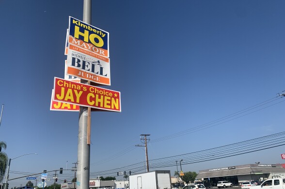 Three signs have been attached to a utility pole that read "Kimberly Ho: Mayor," "Michele Bell: Judge" and "China's Choice: Jay Chen."