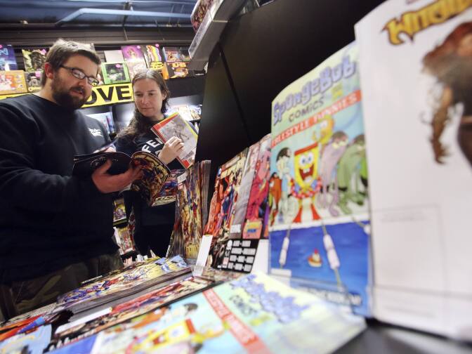 Joe and Kristy Isenbergh, of Boston, browse a selection of free comics at Newbury Comics in Boston, Saturday, May 5, 2012. What began 11 years ago with just four publishers in a few cities has blossomed into an international event involving hundreds of stores in 46 countries with 40 publishers — big, small and self-run — and millions of comic books, all for free. (AP Photo/Michael Dwyer)