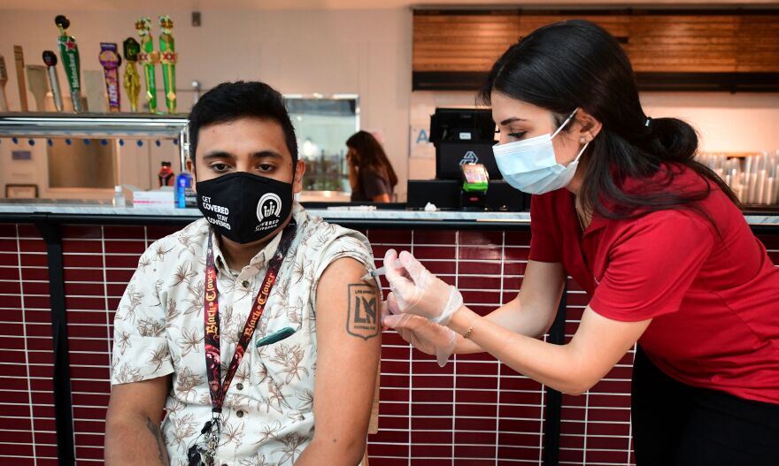 a woman in a red shirt gives a man an injection in his left arm