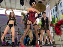 three drag performers on an outdoor stage