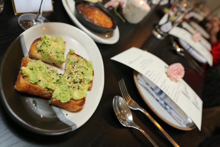 A plate of avocado toast sits next to other empty plates on long tables.