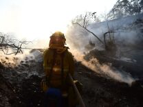 A firefighter controls flames burning in a home at the Skirball Fire in the upscale Bel- Air section of west Los Angeles, California, December 6, 2017.
California motorists commuted past a blazing inferno Wednesday as wind-whipped wildfires raged across the Los Angeles region, with flames  triggering the closure of a major freeway and mandatory evacuations in an area dotted with mansions. / AFP PHOTO / Robyn Beck        (Photo credit should read ROBYN BECK/AFP/Getty Images)
