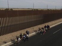TOPSHOT - Central American migrants -mostly Hondurans- moving in a caravan towards the United States in hopes of a better life, walk along the metal fence on the border between Mexicali in Mexico's Baja California State, and Calexico, in California, US, on November 19, 2018. - US President Trump has sent about 5,800 troops to the border to forestall the arrival of large groups of Central American migrants travelling through Mexico and towards the US, in a move critics decry as a costly political stunt to galvanize supporters ahead of midterm elections earlier this month. (Photo by PEDRO PARDO / AFP)        (Photo credit should read PEDRO PARDO/AFP/Getty Images)