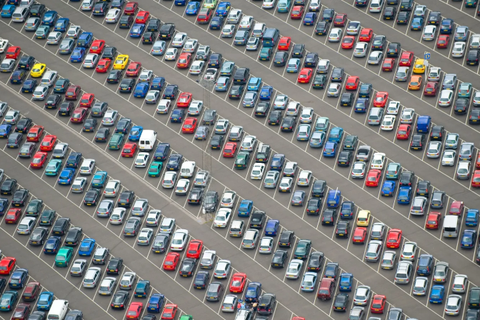 An aerial view of hundreds of cars parked in rows in a large parking lot