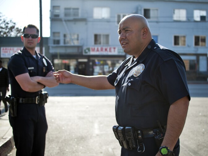 LAPD Officers William Allen, left, and Guillermo Espinoza talk with two people in an argument on the street. Allen and Espinoza are part of LAPD's central station where the body cameras will be tested out for 90 days.