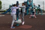 Children playing on playground structures. The structure is blue and made up of two slides and climbing apparatuses