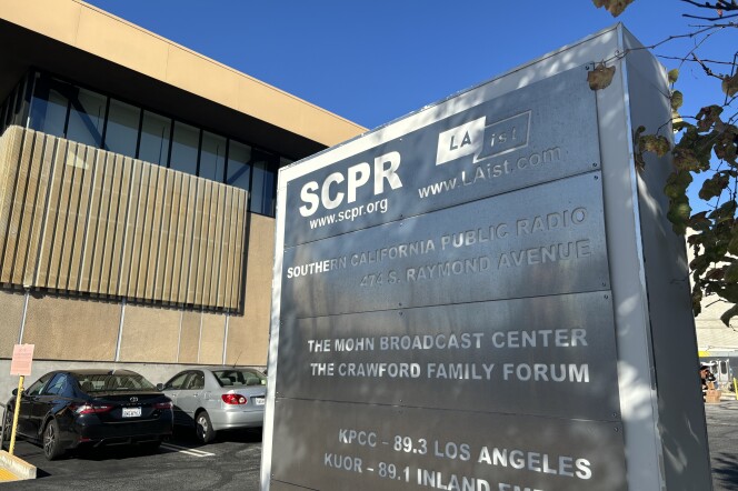 A metal sign outside a large beige building lists SCPR and LAist side-by-side.