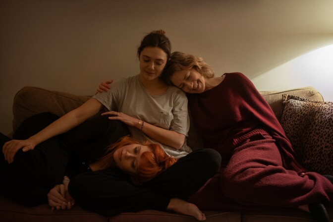 Three women sit together on a couch 