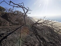A burned-over bluff still smoulders and traffic on Pacific Coast Highway is jammed in the Pacific Palisades area of Los Angeles Wednesday, Jan. 15, 2014, after a fire threatened bluff top homes Tuesday afternoon. The flames crept within feet of multimillion-dollar cliff-top homes, but none were damaged.  The fire was knocked down in about 1 1/2 hours, but the highway remained closed for several hours more until one lane opened in each direction.  Santa Ana winds, generated by strong surface pressure anchored over the West, were predicted to remain at advisory levels until noon Wednesday. Red-flag warnings for fire danger were expected to remain in effect until Wednesday evening. (AP Photo/Reed Saxon)