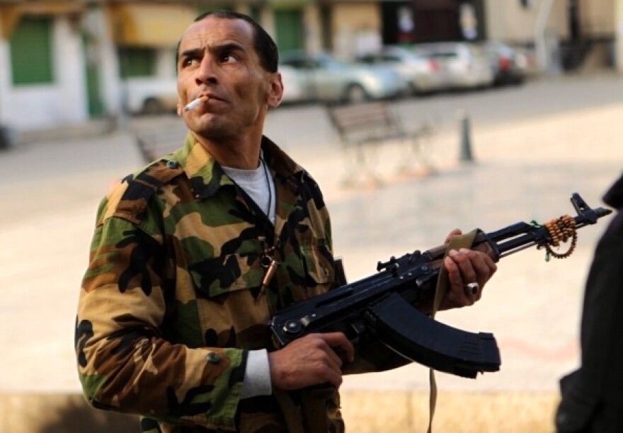 A Libyan rebel searchs for snipers as they protect a march gathering thousands of people in the streets of Benghazi on March 23, 2011 to show their support for an internationally-enforced no-fly zone over Libya. 