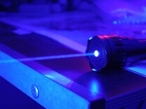 This is a picture of my 1200mW 445nm vacuum wavelength semiconductor diode class 4 very high-power blue laser with no lenses attached (only the built-in focusing/collimating lens) lasing in the dark.  The beam is extremely pronounced due to <a href="http://en.wikipedia.org/wiki/Rayleigh_scattering" rel="nofollow">Rayleigh scattering</a> and dust in the air (visible as streaks in the beam).  Aside from the red light used to provide a counterbalance to the blue light of the laser, the laser was the only active light source in my room when I took this photo.  All the blue light visible is due to reflective scatter from the wall the (focused) laser beam was striking.

Fun fact: By my calculations, this laser emits about 2.69e18 (that's 2,690,000,000,000,000,000) photons per second.

Now, for the obligatory "DANGER BIG SCARY LASER" warning:
<b><i><u>DANGER</u>:</i> The laser shown here is a class 4 laser device.  Class 4 lasers are <u>NOT</u> laser pointers, and should never be used for that purpose.  Despite the fact that I took the picture with the laser sitting on my desk, and despite the fact that I seem to have fun when using my lasers (I do), I took proper safety precautions to ensure that myself and others do not get injured; for example, I wore ANSI Z87.1-standard blue laser safety goggles at all times when the laser was operating.

CLASS 4 LASERS ARE THE MOST DANGEROUS KIND OF LASER.  All exposure (especially direct contact with skin) to the beam should be avoided, and these lasers are a fire hazard.  Proper precautions must be taken to ensure the safety of people and property.

In other words, unless you know what you're doing, <u>DO NOT TRY THIS AT HOME</u>.  You could inadvertently blind yourself or someone else.  And, of course, high power laser devices should <u>NEVER</u> be pointed at other people, and lasers of any kind should <u>NEVER</u> be pointed at aircraft, <i>especially</i> those in flight.  High-power lasers like this one should be treated with the same respect as you would treat a loaded gun.

Please be aware that high power laser devices may be restricted by laws in your area.</b>

<b><i><u>HIGH-ENERGY VISIBLE LIGHT WARNING:</u></i> Lasers emitting in the blue and violet parts of the visible light spectrum (high-energy visible light, HEV light) present an additional hazard to eyes.  Prolonged exposure to HEV light, even at relatively low power levels, can cause permanent damage to eyesight.  Please see <a href="http://en.wikipedia.org/wiki/High-energy_visible_light" rel="nofollow">here</a> for more information.</b>