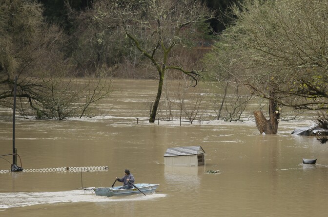 A man uses a rowboat to make his way through a flooded RV park as the Russian River flows in the distance on Jan. 9, 2017, near Forestville, Calif. A massive storm system stretching from California into Nevada lifted rivers out of their banks, flooded vineyards and forced people to evacuate after warnings that hillsides parched by wildfires could give way to mudslides. 