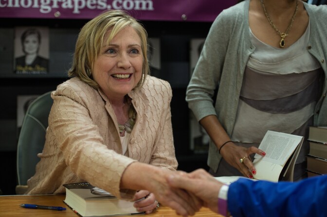 Former US Secretary of State Hillary Clinton shakes hands with an attendee as she signs her book 'Hards Choices' at the Bunch of Grapes bookstore on Martha's Vineyard on August 13, 2014. Clinton on August 12 denied attacking US President Barack Obama over his foreign policy in Syria and Iraq, insisting she was looking forward to 'hugging it out' with the US leader when they meet at a party later this week. 