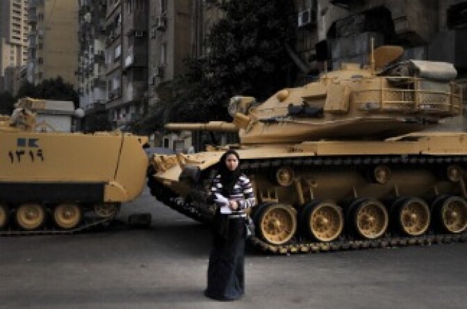 An Egyptian woman stands in front of tanks blocking the street during a demonstration by Coptic Christians.