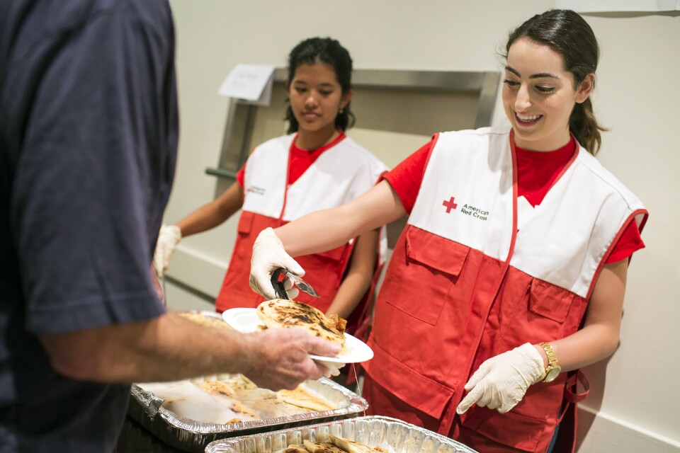 Red Cross Intern Shaghig Tchaparian, right, based out of their Arcadia office, serves food to residents staying at an evacuation center inside the Duarte Community Center during the San Gabriel Complex fire on Tuesday, June 21, 2016. The food was donated by El Salvadoreno Papuseria.