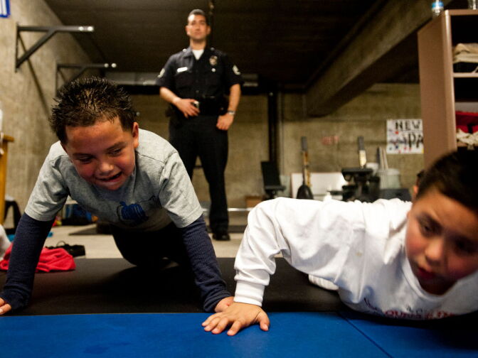 Eight-year-old Guiermo Reyes, left, does push-ups as PAL supervisor Sgt. James Townsend watches kids warm up during the 5 p.m. class.