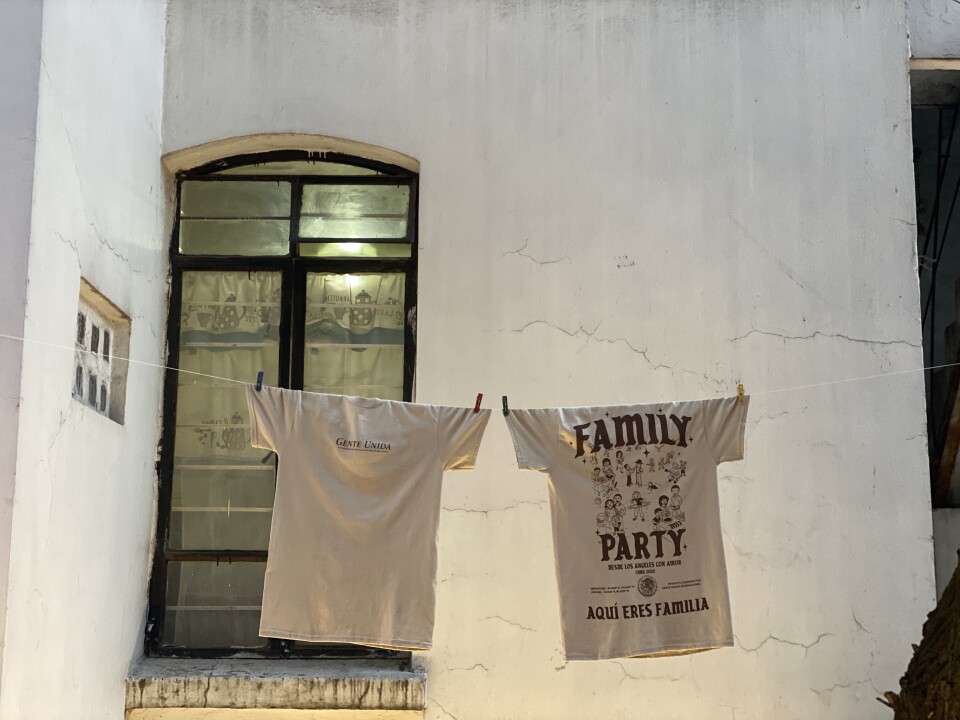 Two t-shirts — which are the Family Party mech — hang on a clothesline. The words Family Party are written on the khaki shirt.