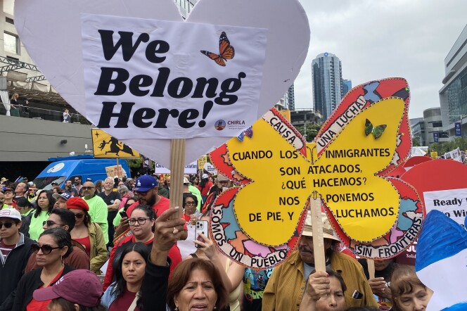 A crowd of people carrying colorful signs in downtown Los Angeles.