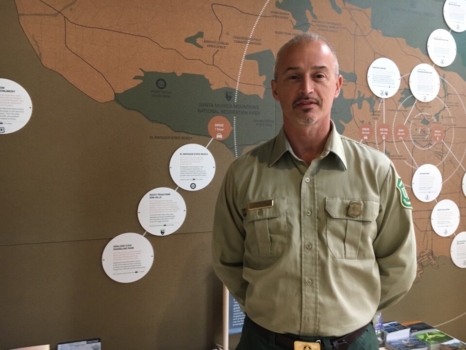 Jeff Vail, with the Angeles National Forest, next to a map that shows access to hiking and recreational areas near to urban L.A.