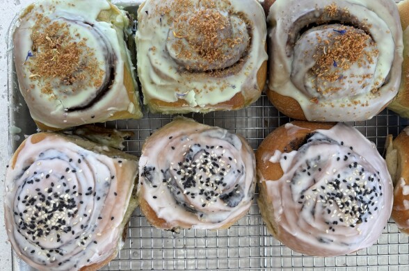 An enticing batch of gourmet cinnamon rolls with Asian-inspired flavor twists, arranged neatly on a cooling rack atop a baking tray.