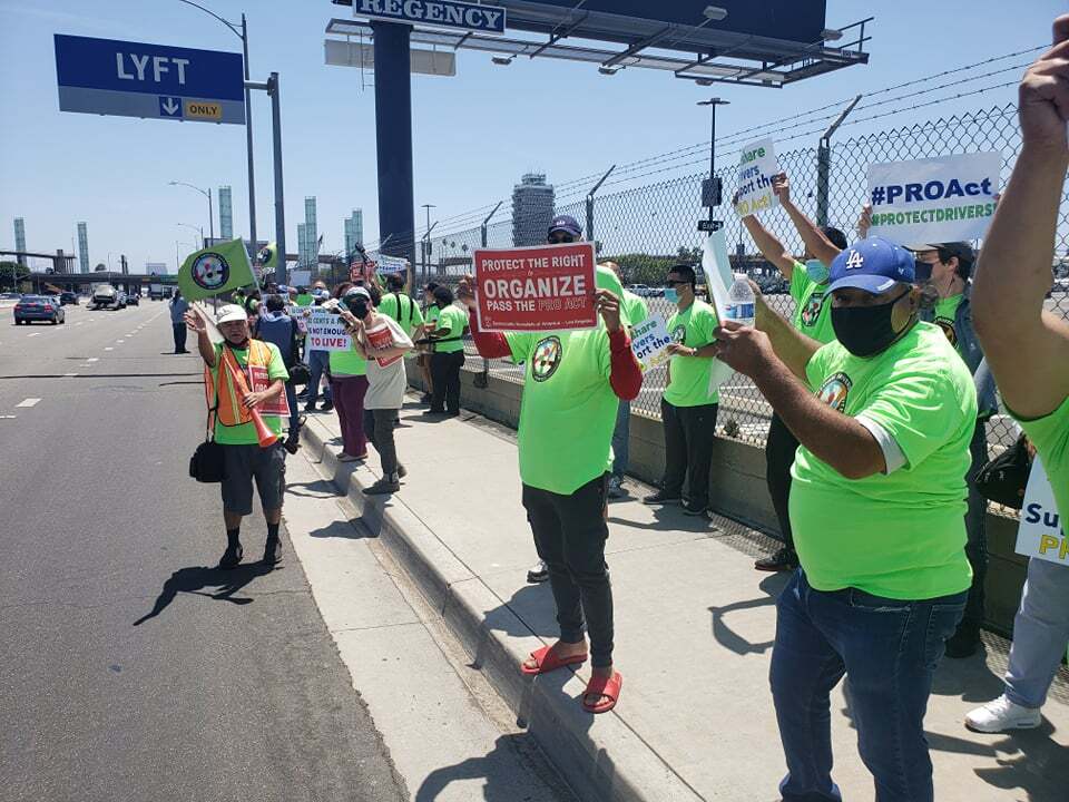 Protestors line up on the side of road holding signs in support of the PRO Act.