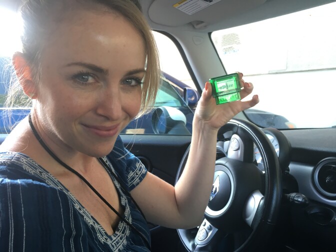 KPCC's transportation reporter, Meghan McCarty, shows the mile-tracking device she's installing in her car as part of a Caltrans pilot program testing per-mile charges versus taxes at the pump.