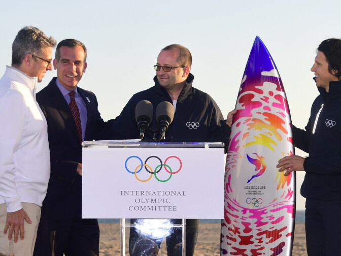 Patrick Baumann (C) and Christophe Dubi (R) of the International Olympic Committee react upon being given a surfboard by Los Angeles Mayor Eric Garcetti and Casey Wasserman (L) of LA 2024 before a press conference at Santa Monica Beach as the International Olympic Committee Evaluation Commission wrap up their visit to Los Angeles on May 11, 2017.
 / AFP PHOTO / FREDERIC J. BROWN        (Photo credit should read FREDERIC J. BROWN/AFP/Getty Images)