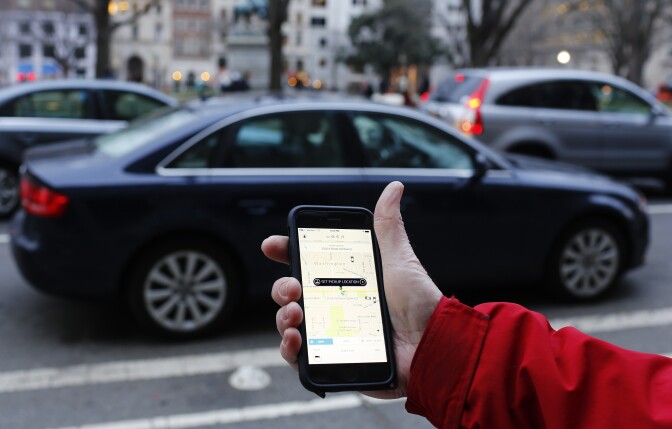 An Uber application is shown as cars drive by in Washington, D.C. on March 25, 2015.