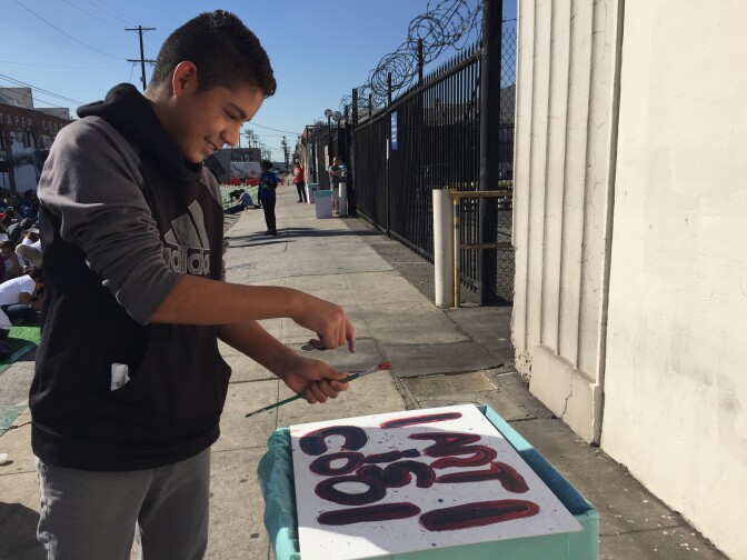 George Washington Carver Middle School 7th grader Diego Castañeda splatters paint on his canvas, which reads "ART IS COOL." He hopes to be a cartoonist or another type of artist when he grows up. 