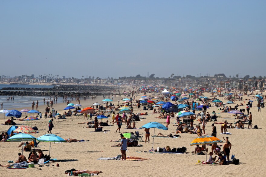 Beach-goers relax on a sandy beach under colorful umbrellas.
