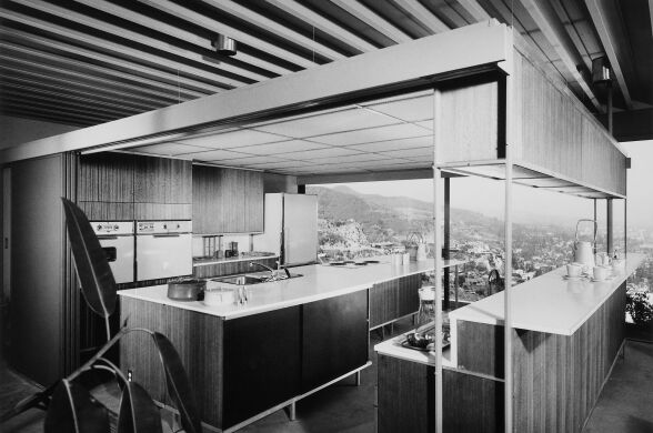 A black and white photo of a kitchen with lots of rectangular cabinets.