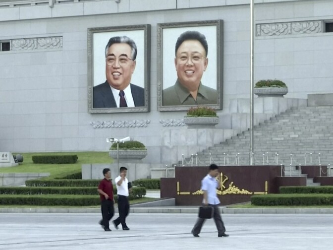 In this image made from video, pedestrians walk beneath portraits of Kim Il Sung, left, and Kim Jong Il, at Kim Il Sung square in Pyongyang, North Korea, Friday, Aug. 11, 2017. Despite tensions and talk of war, life on the streets of the North Korean capital Pyongyang remained calm. (AP Photo)