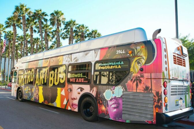 The exterior of a Metro bus covered with a colorful collage of portraits in different art styles.