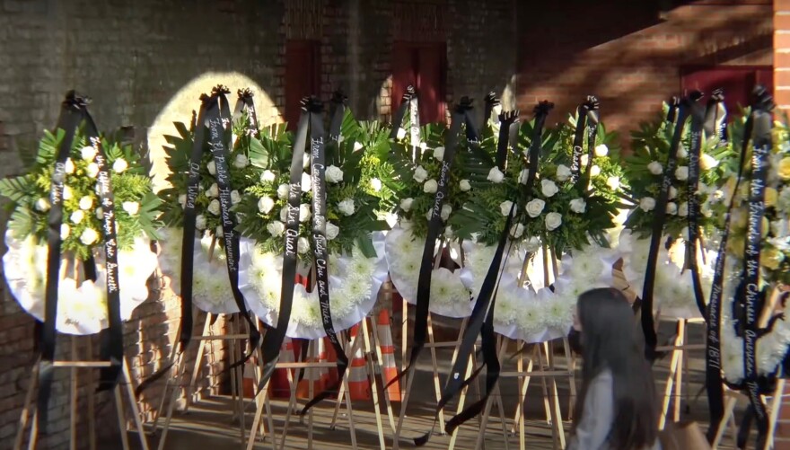 A woman walks past rows of giant white floral wreaths set up at a commemoration ceremony for the victims of the 1871 Chinese massacre.