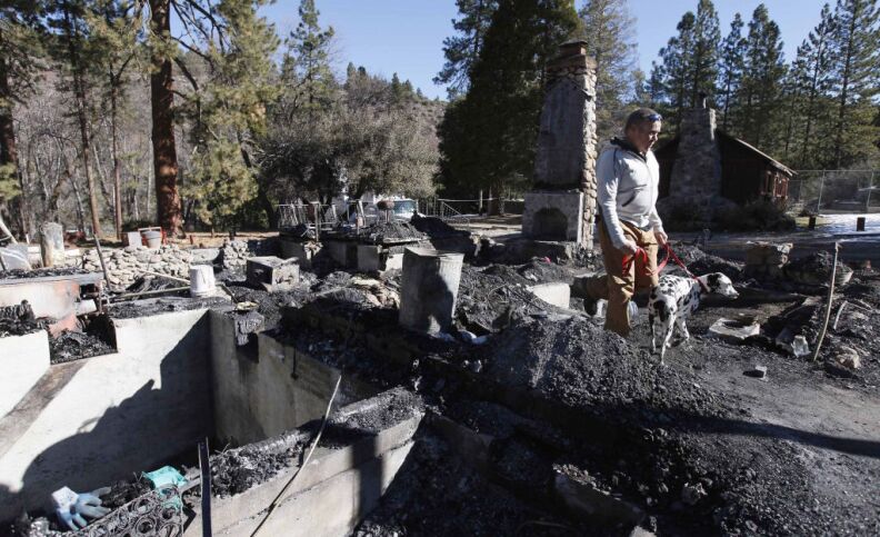 Rick Heltebrake with his dog Suni looks over the burned-out cabin where Christopher Dorner's remains were found after a police standoff Tuesday near Big Bear, Calif., Friday Feb. 15, 2013. Earlier, Heltebrake had been carjacked by Dorner.