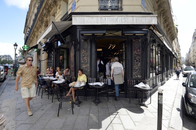 People sit at a cafe at a crossroad on the Ile Saint Louis island in central Paris in July 2013. 