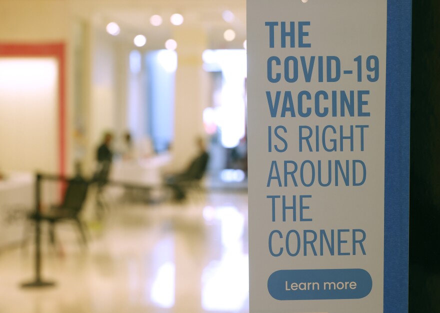 A sign reads: THE COVID VACCINE IS RIGHT AROUND THE CORNER