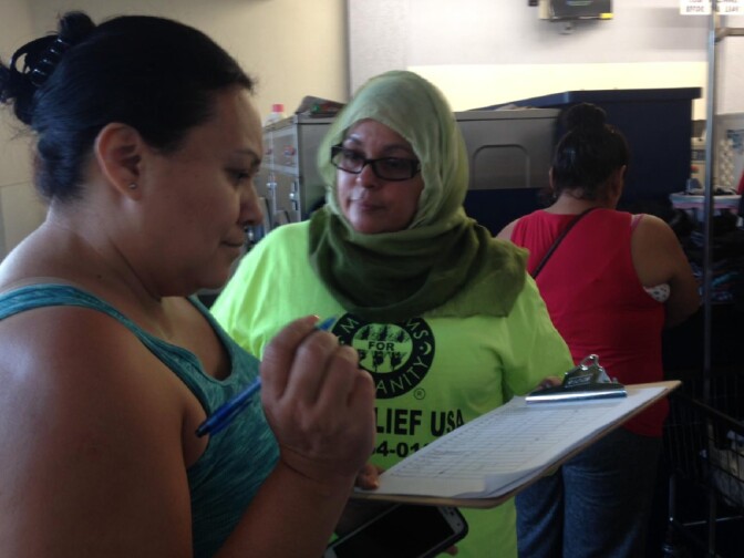A volunteer with Islamic Circle of North America Relief signs up a women for the free laundry event at an Anaheim laundromat.