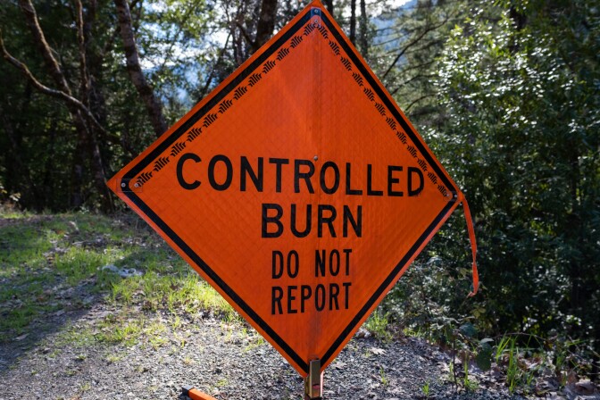An orange sign with "controlled burn do not report" written on it.